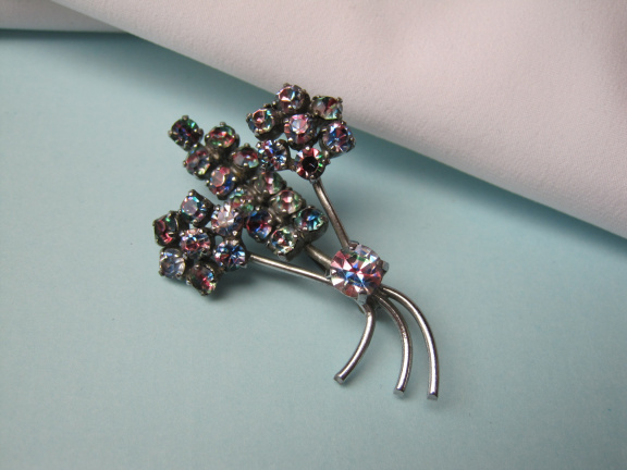 Broche zilverkleurig bloemtakje met regenboog kristal rijnstenen. 4.8x3.1 cm. - nr. 1